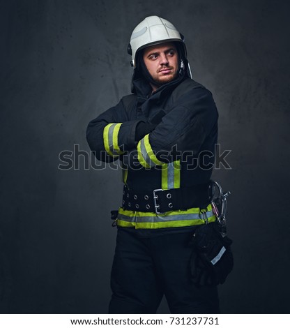 Studio portrait of firefighter dressed in uniform and safety helmet.