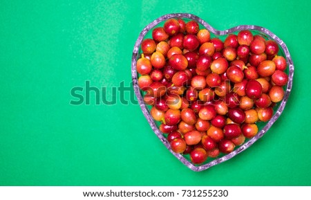 Heart shape made from red coffee beans on green background.