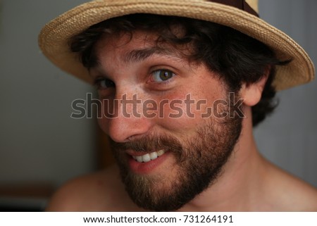 Profile portrait of a young, handsome, bearded caucasian man looking out from under a yellow fedora.