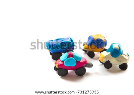 four multi-colored cars made by child of clay on a white background.