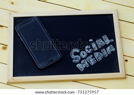 Social media concept with smartphone and word SOCIAL MEDIA written on blackboard.