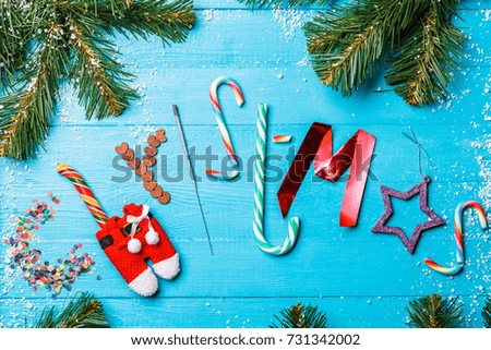 Picture of blue table with spruce branches, word Christmas from sweets, Bengal fire, spangles, Santa clothes