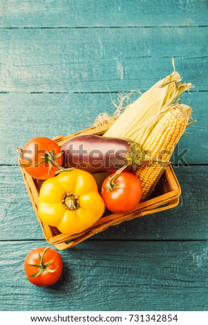 Toned photo of basket with autumn vegetables on blue wooden table