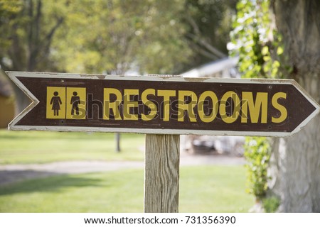 A wooden Restrooms sign with arrow