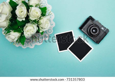 vintage retro camera on wooden table background with blanks photo to placed your pictures, bouquet of pink roses, gift boxes and heart made from film. valentines day background. top view