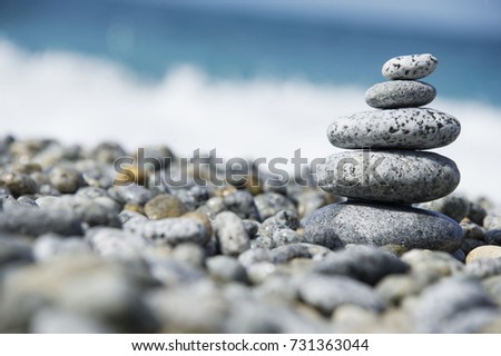 Stones pyramid on pebble beach, stability, zen, harmony, balance concept. With blur sea background on a sunny day in italy