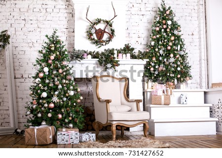 Christmas tree and a chair stands near the fireplace  and other holiday decorations in white loft Royalty-Free Stock Photo #731427652