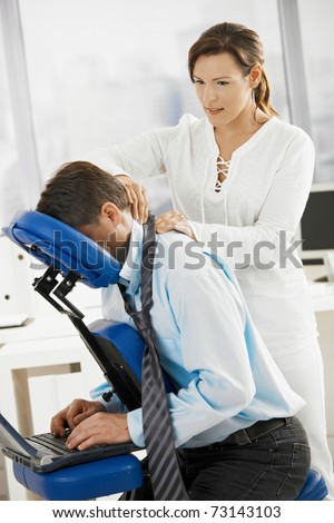 Businessman sitting on massage chair, getting back massage.?