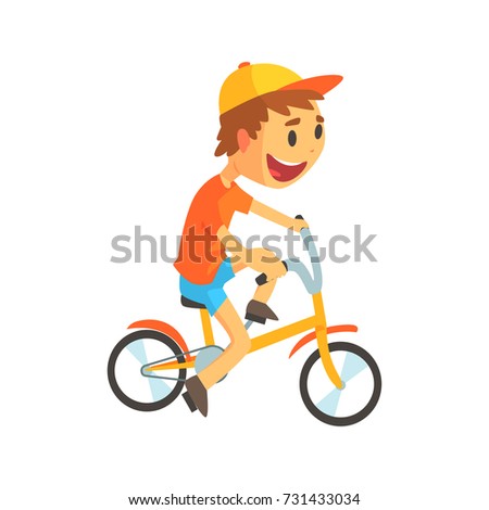 Funny little boy in yellow baseball cap riding bicycle