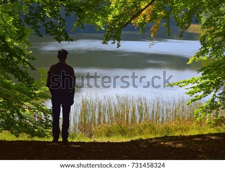 silhouette of man stand  and watching view from lake 