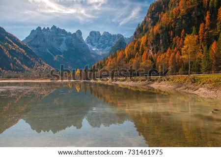 Autumn scenery of Lake Landro - Lago di Landro - Durrensee - with snow-capped Dolomite Mountains on background and beautiful reflections on smooth lake water at the sunny autumn day, Italy