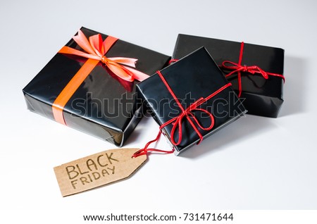 Three black wrapped gift boxes with a red cord and a Black Friday sales tag handwritten on a cardboard
