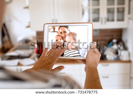 Father at home with tablet, video chatting with his family. Royalty-Free Stock Photo #731478775
