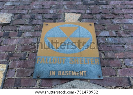 Old faded Fallout Shelter Sign on grungy Brick Wall background