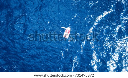 Aerial bird's eye drone photo of small sailboat cruising in deep blue sea