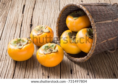 fresh persimmon fruit and basket on old wood ( Diospyros virginiana L., EBENACEAE)