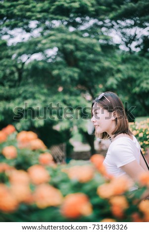 Beautiful young woman smiling with flower and tree as background