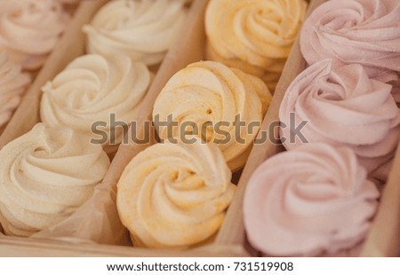 Biscuit meringue with an air cream of different colors in box for sale, inside a sweet shop.