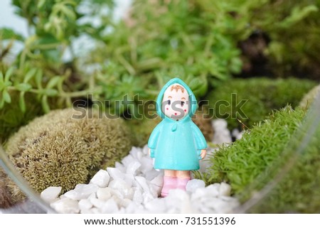 A little girl in her green raincoat standing in the terrarium