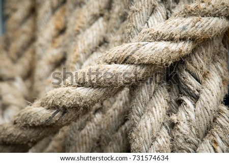 Macro close up on rough braided hemp cordage crossing diagonally with coils of rope in the background