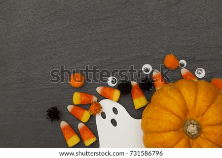 Halloween background with ghosts and candy corn on a slate background