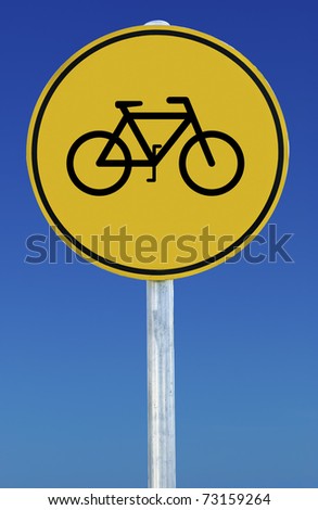 Circular yellow sign on blue sky background. Sign features a picture of a bicycle