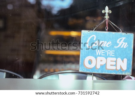 Open sign board close up through the glass of a window at coffee shop window. Shallow depth of field. Royalty-Free Stock Photo #731592742