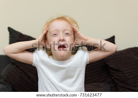 Young girl on sofa at home crying with hands on her head. Royalty-Free Stock Photo #731623477