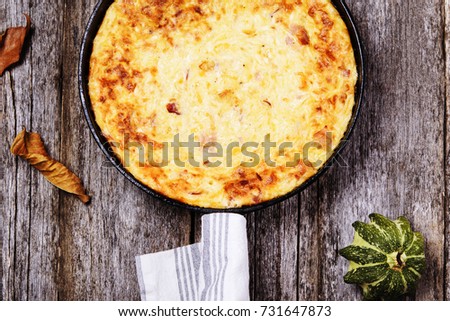 Zucchini, bacon and cheese casserole or gratin in cast-iron pan on vintage wooden table. Selective focus 