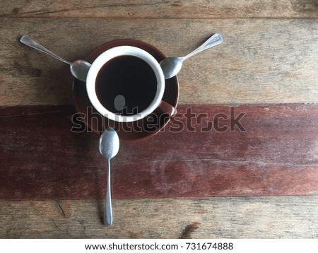 A cup of coffee and three spoons on wooden table