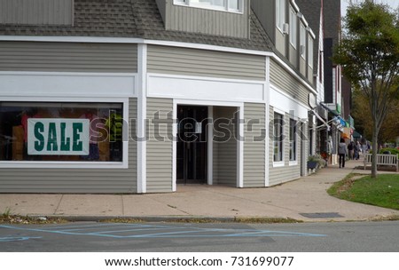 Day time exterior generic no signage retail clothing storefront on a main street in small town anywhere USA. People window shop up and down sidewalk