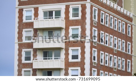 Generic large apartment building day time exterior. Red brick design close up establishing photo. No signage. Condo or hotel type of structure.