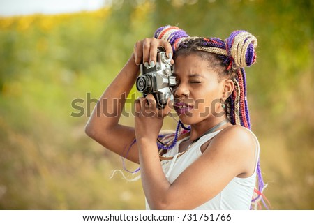 happy young african american female photographer looking to vintage camera
