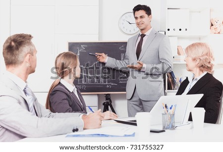 Confident businessman discussing new business project with members of his team