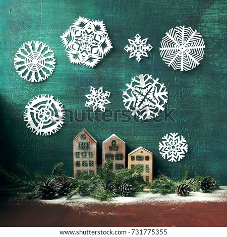 A New Year and Christmas card / a miniature wooden houses ,paper cut snowflakes and spruce branches on the blue wooden background with inscription