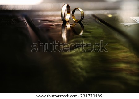 Unusual Jewelry Photo. Wedding Rings on abstract dark background with water drops