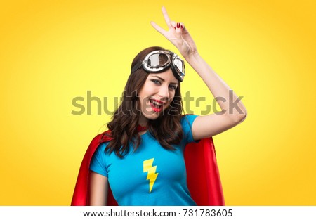 Pretty superhero girl making victory gesture on colorful background