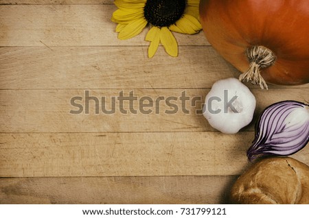 PLants and vegetables on wooden table. Pumpkin with sunflower and bread with other vegetables and food on wooden board. Vegan food. View from above with place for text. Copy space vegetables (meal).
