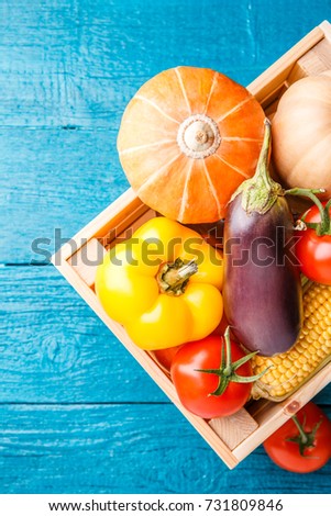 Picture from above of wooden box with autumn vegetables on blue wooden table