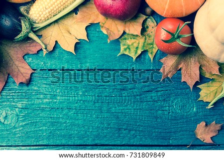 Toned image of autumn leaves, pumpkin, tomato, pomegranate, on blue wooden table with space for text