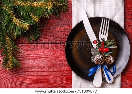 Photo of Christmas table with fork and knife on plate, spruce branches