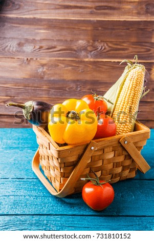 Photo of basket with autumn vegetables on blue wooden table