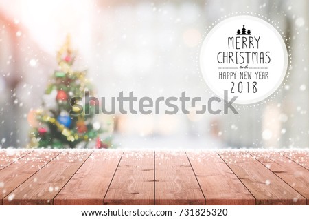 Wood table top on blur with bokeh christmas tree background with snowfall and Merry Christmas & Happy New Year 2018 sign - can be used for display or montage your products.