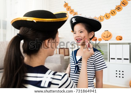 pirate girl and mother play Halloween makeup game and sketch scars on the face at home