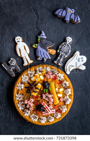 Halloween bakery and sweets. Pumpkin pie, gummy spiders, gingerbread cookies on black background top view