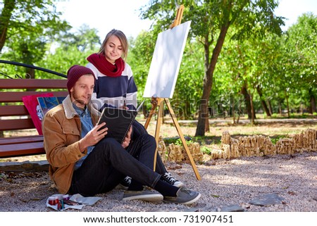 The guy and the girl are watching the pictures in their album for drawing