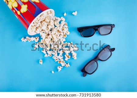 Popcorn and 3d glasses on a blue background. The concept is recreation, cinema.