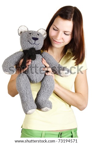 young girl in yellow shirt holding soft bear toy, smiling and looking on it, isolated