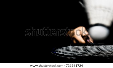 Man is playing the badminton and shuttlecock in the air on dark background