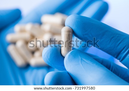 Scientist hands in gloves hold pills, new pill research concept Royalty-Free Stock Photo #731997580